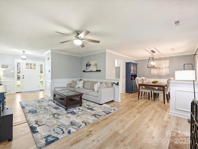 living room featuring ceiling fan with notable chandelier, light hardwood / wood-style flooring, and ornamental molding