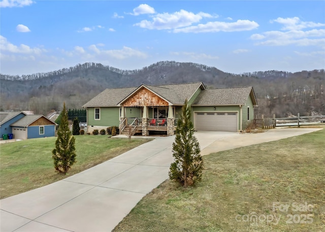 view of front of house with a porch, a garage, a mountain view, and a front yard