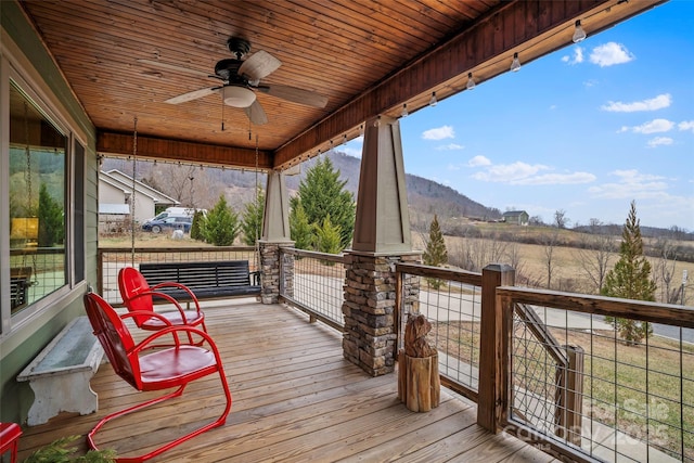 wooden deck with a mountain view, ceiling fan, and covered porch