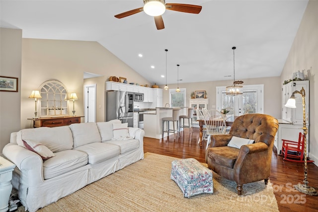 living room with hardwood / wood-style flooring, ceiling fan with notable chandelier, and high vaulted ceiling