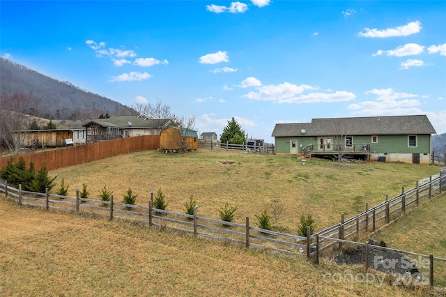 view of yard with a deck with mountain view, a shed, and a rural view