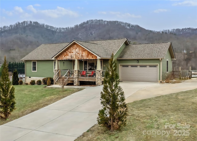 view of front facade featuring a garage, a mountain view, covered porch, and a front lawn