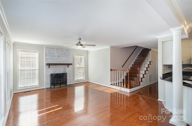 unfurnished living room featuring hardwood / wood-style flooring, ornamental molding, a brick fireplace, and a healthy amount of sunlight