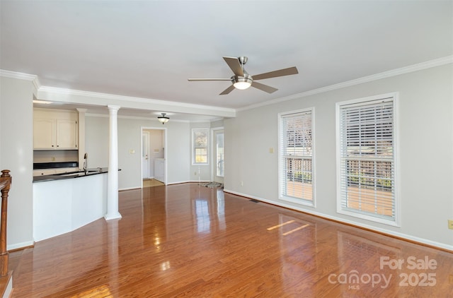 unfurnished living room featuring wood-type flooring, ornamental molding, sink, and ceiling fan