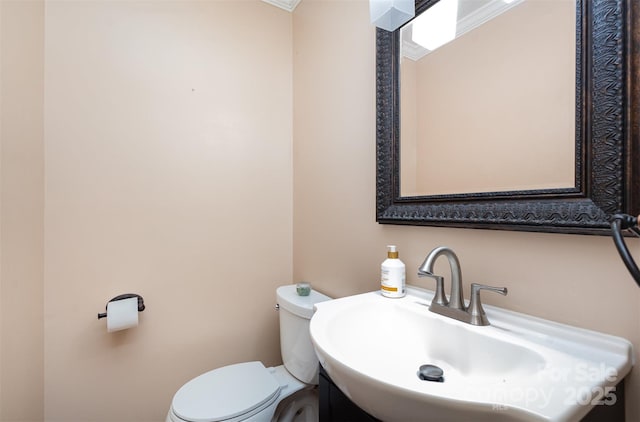 bathroom featuring ornamental molding, toilet, and sink