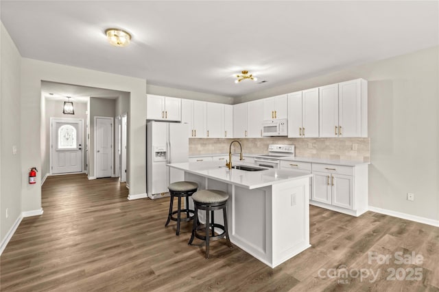 kitchen featuring white cabinetry, sink, an island with sink, and white appliances