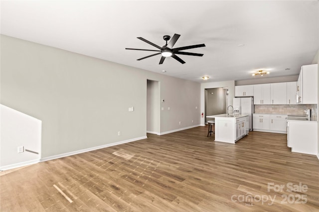 kitchen with a kitchen island with sink, white cabinets, a kitchen breakfast bar, and white fridge with ice dispenser