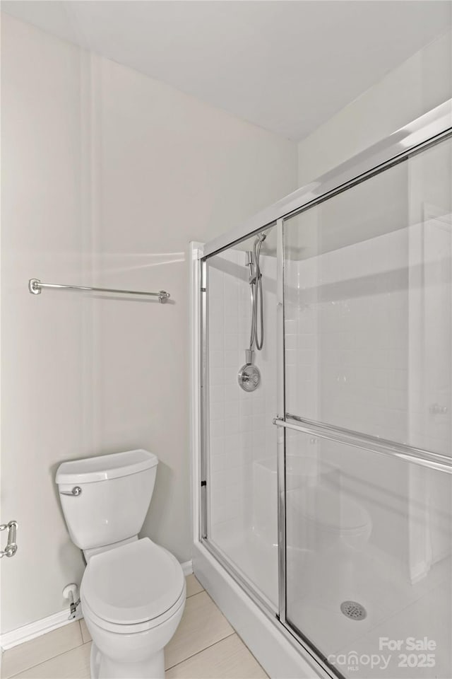 bathroom with tile patterned floors, toilet, and an enclosed shower