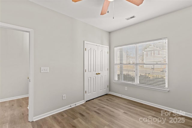 unfurnished bedroom featuring ceiling fan, light hardwood / wood-style floors, and a closet