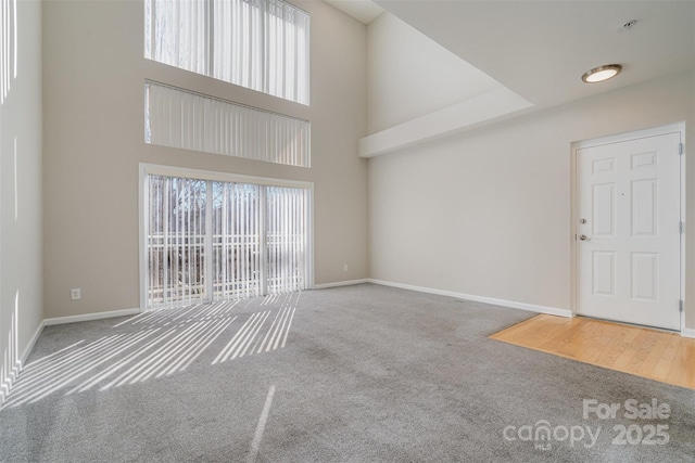 unfurnished living room with carpet and a towering ceiling