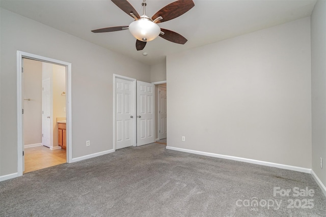 unfurnished bedroom featuring light carpet, ceiling fan, ensuite bathroom, and a closet