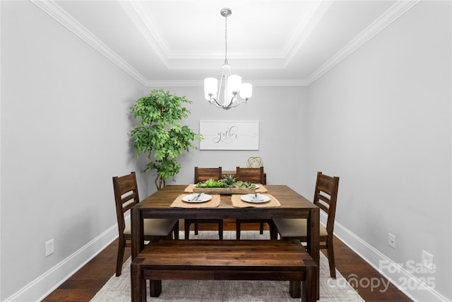 dining room with wood-type flooring, a notable chandelier, and a tray ceiling