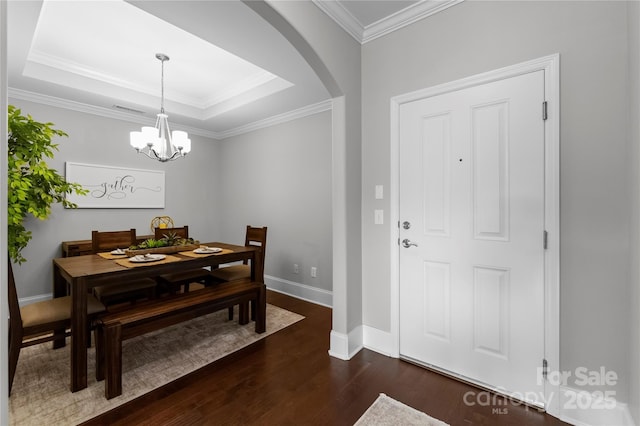 dining space with crown molding, dark hardwood / wood-style floors, a raised ceiling, and a chandelier