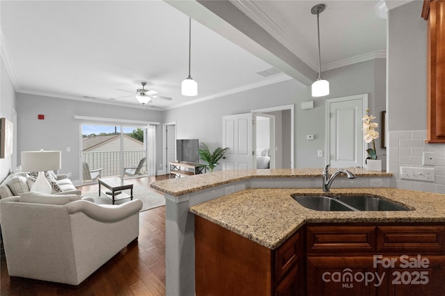 kitchen with dark wood-type flooring, light stone counters, sink, and hanging light fixtures