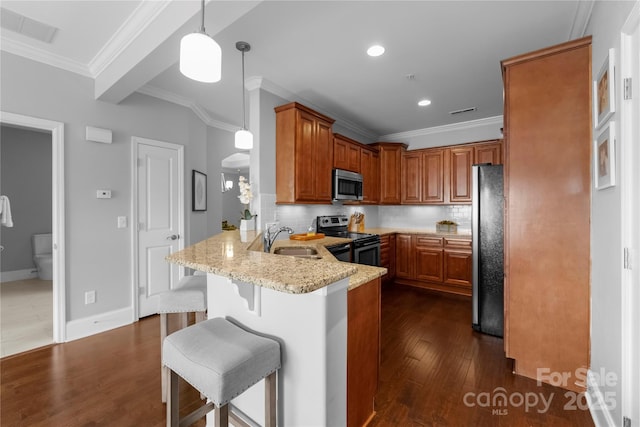 kitchen with pendant lighting, sink, appliances with stainless steel finishes, light stone counters, and kitchen peninsula