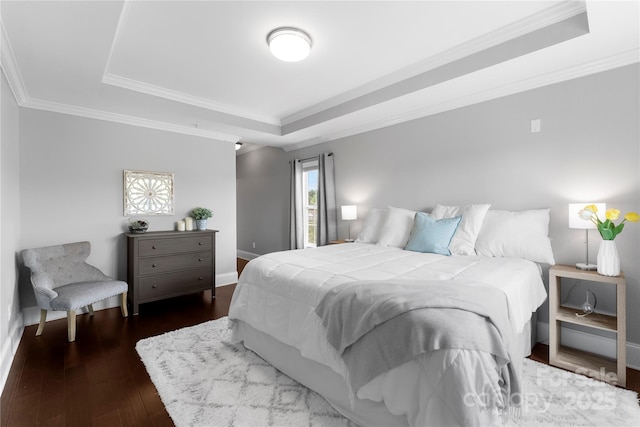 bedroom with dark hardwood / wood-style flooring, a tray ceiling, and ornamental molding