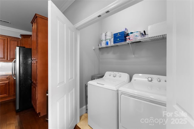 laundry room featuring washing machine and dryer, wood-type flooring, and crown molding