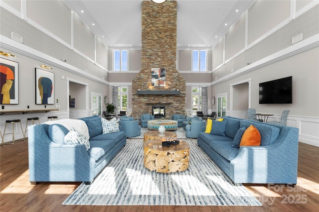 living room featuring hardwood / wood-style flooring, a towering ceiling, and a fireplace