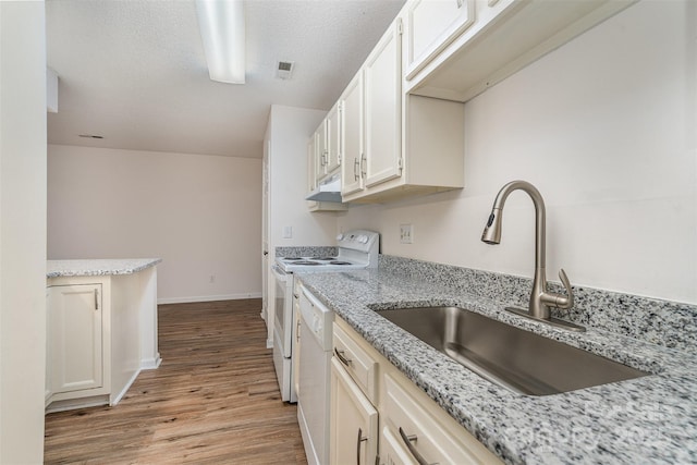 kitchen with sink, a textured ceiling, light stone counters, white appliances, and light hardwood / wood-style flooring