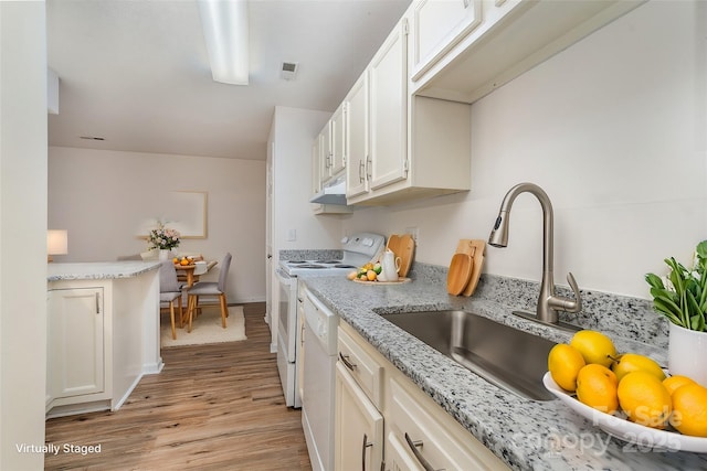 kitchen with white appliances, visible vents, light stone counters, light wood-type flooring, and under cabinet range hood