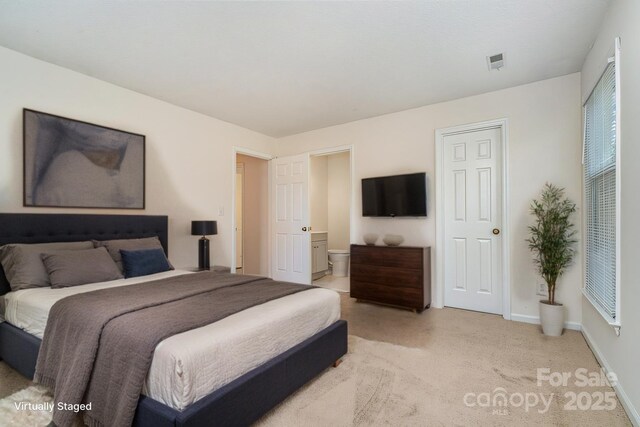 bedroom with light carpet, connected bathroom, visible vents, and baseboards