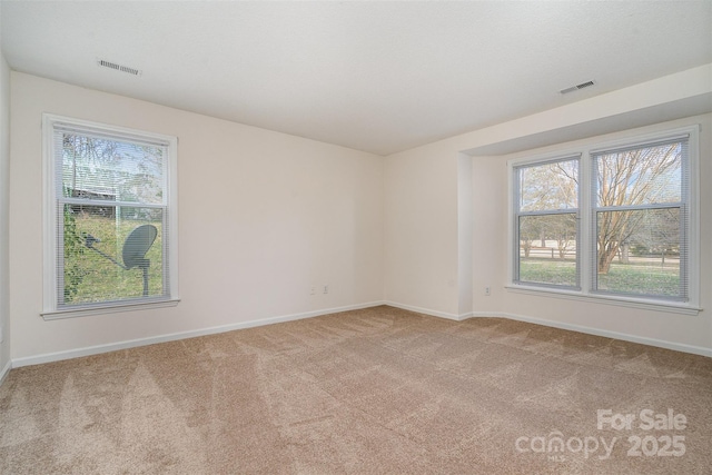 empty room featuring visible vents, light carpet, and baseboards