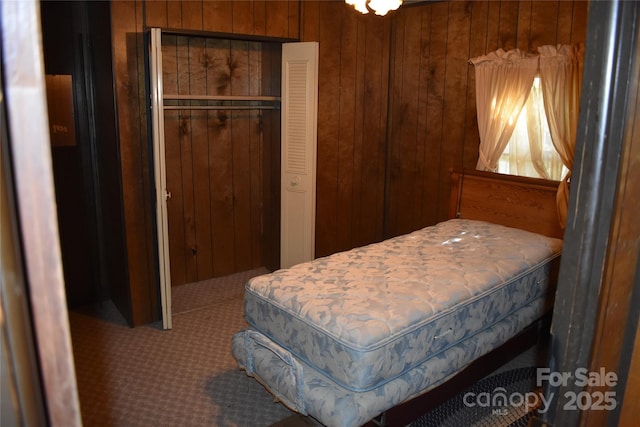 bedroom with carpet, wood walls, and a closet