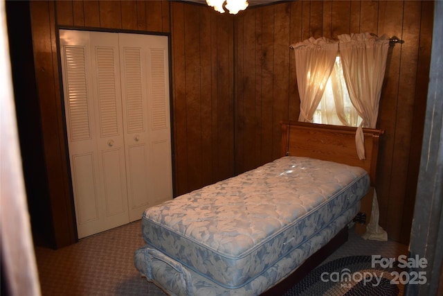 carpeted bedroom with a closet and wood walls