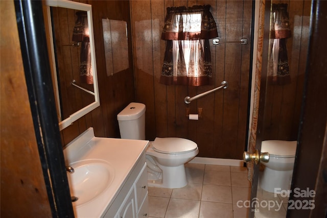 bathroom with vanity, toilet, tile patterned floors, and wood walls