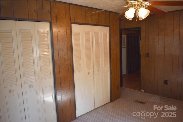 unfurnished bedroom featuring ceiling fan and wooden walls