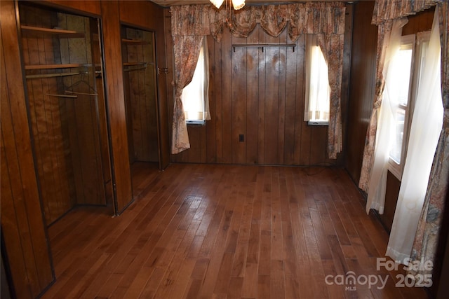 unfurnished dining area with a wealth of natural light, dark hardwood / wood-style floors, and wood walls