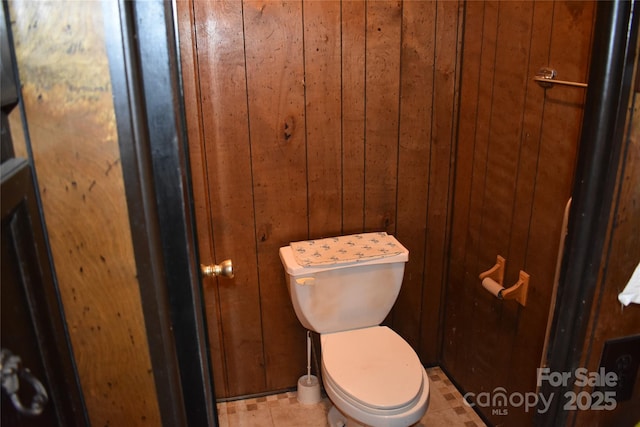 bathroom with toilet and wooden walls