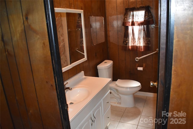 bathroom with toilet, tile patterned floors, wooden walls, and vanity