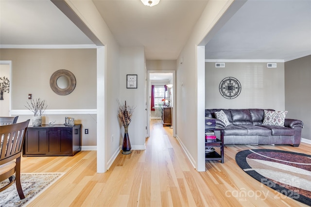 hall with ornamental molding and light wood-type flooring