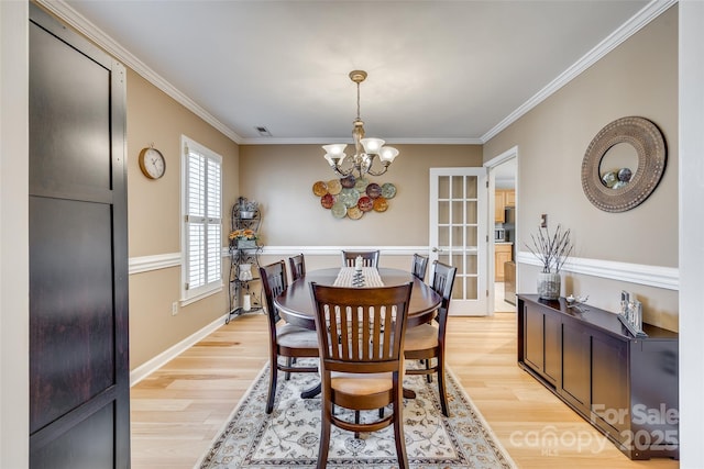 dining space featuring a notable chandelier, crown molding, and light hardwood / wood-style flooring