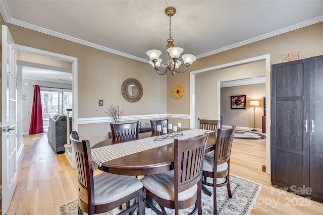 dining area with an inviting chandelier, light hardwood / wood-style flooring, and ornamental molding