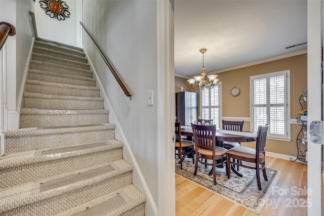 staircase featuring crown molding, a notable chandelier, and hardwood / wood-style flooring