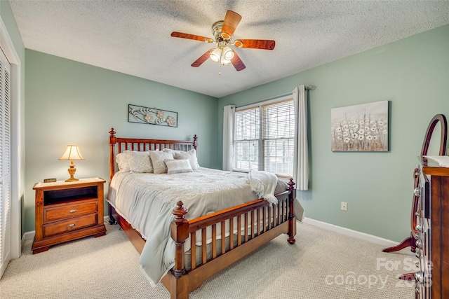 bedroom with ceiling fan, light colored carpet, a closet, and a textured ceiling