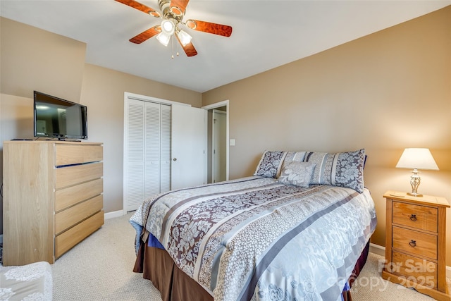 bedroom with ceiling fan, light carpet, and a closet