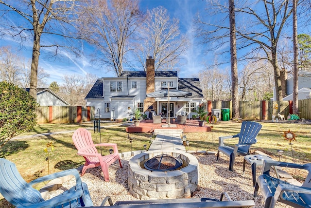 back of property featuring a wooden deck, a lawn, and a fire pit