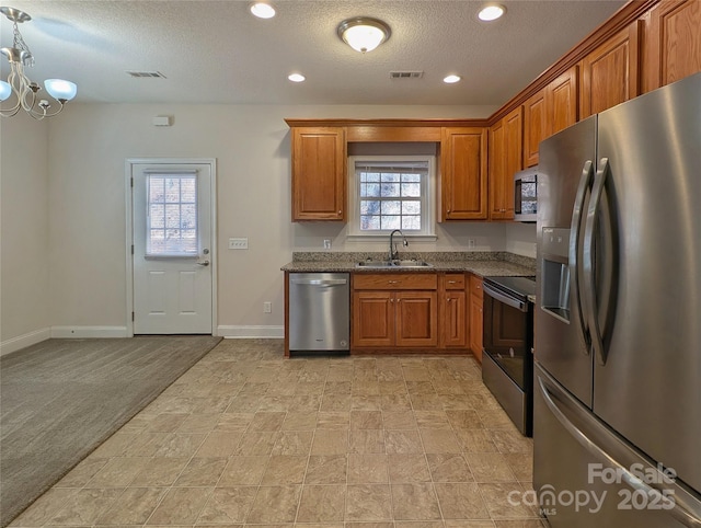 kitchen featuring appliances with stainless steel finishes, sink, light colored carpet, a notable chandelier, and a textured ceiling