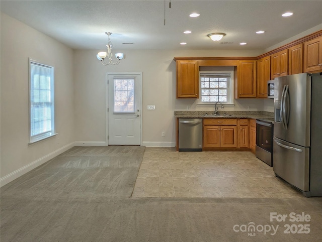 kitchen with a healthy amount of sunlight, light colored carpet, appliances with stainless steel finishes, and sink