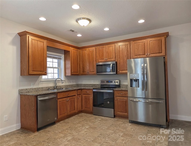 kitchen featuring appliances with stainless steel finishes, sink, a textured ceiling, and dark stone countertops