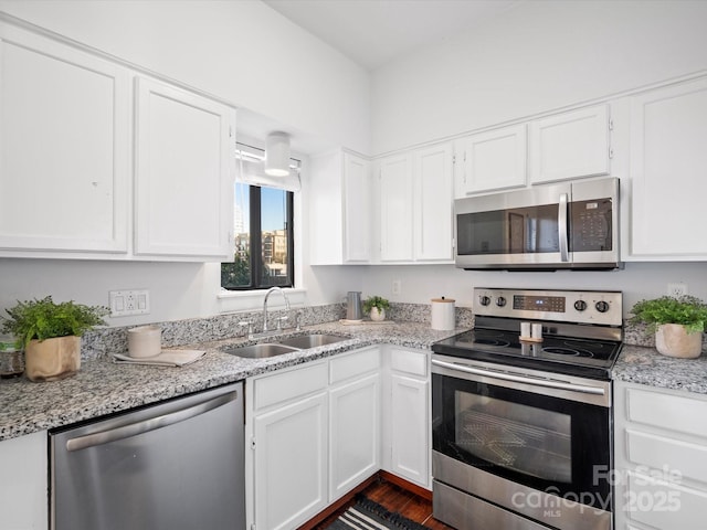 kitchen with appliances with stainless steel finishes, sink, white cabinets, and light stone counters