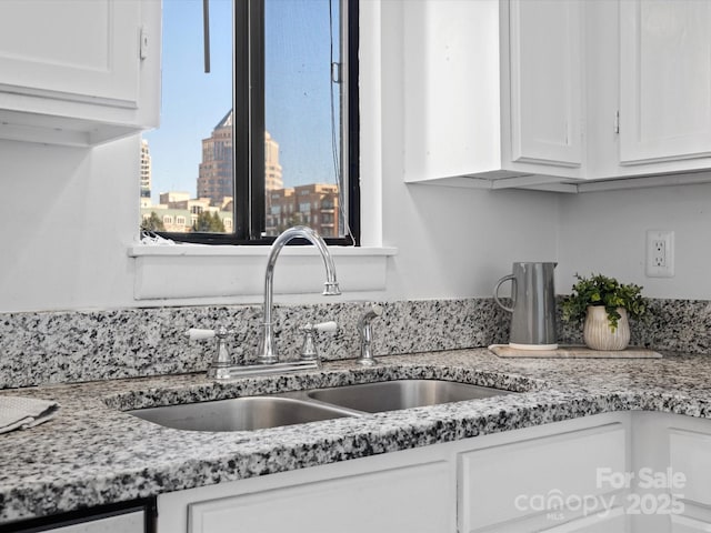 kitchen featuring white cabinetry, light stone countertops, and sink