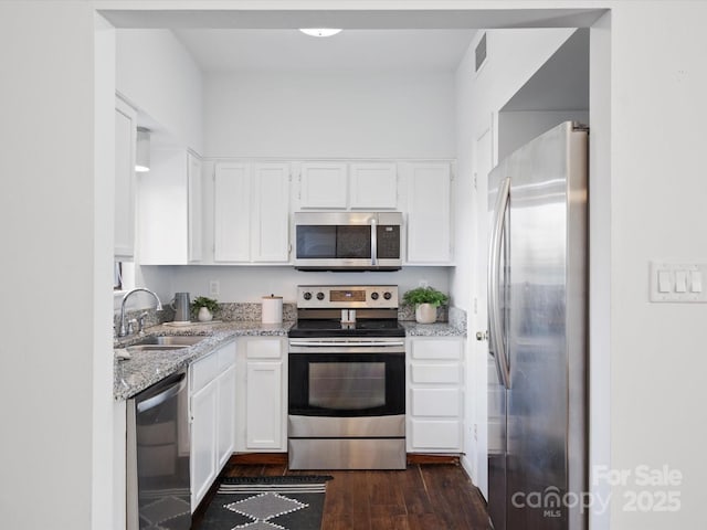 kitchen featuring sink, white cabinetry, dark hardwood / wood-style flooring, stainless steel appliances, and light stone countertops