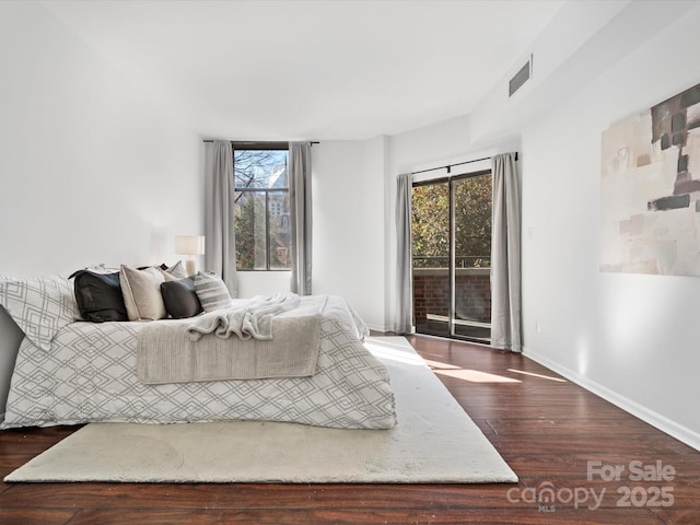 bedroom featuring dark hardwood / wood-style flooring, multiple windows, and access to outside