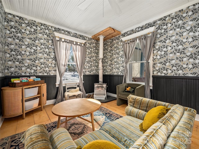 living room featuring hardwood / wood-style floors, a wood stove, and crown molding