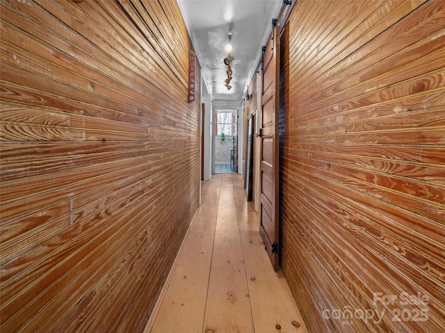 hallway featuring wood walls and a barn door