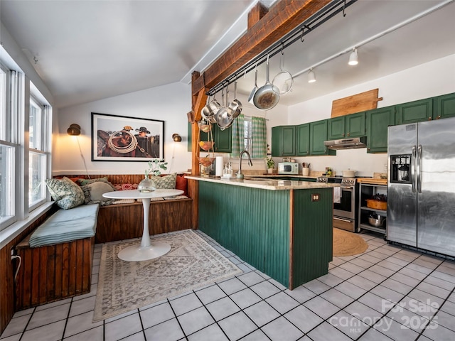 kitchen featuring green cabinetry, lofted ceiling, light tile patterned flooring, kitchen peninsula, and appliances with stainless steel finishes